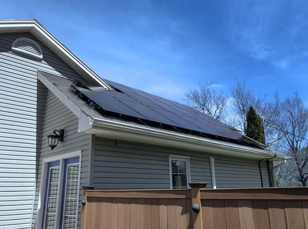 Residential renewable solar energy project on rooftop of a white house with blue sky