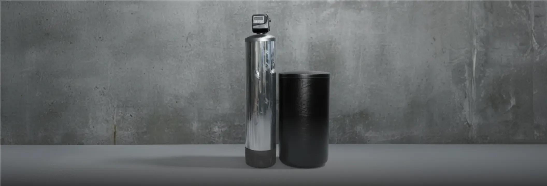 A home water treatment filtration system featuring a stainless steel conditioning tank and a black water softener brine tank.