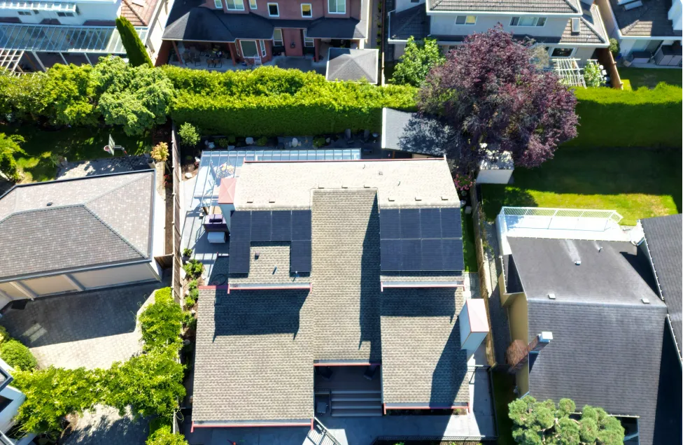 Aerial shot of a sleek, modern solar panel system on a BC residence, optimized for maximum energy harvesting under the BC Hydro self-generation program.