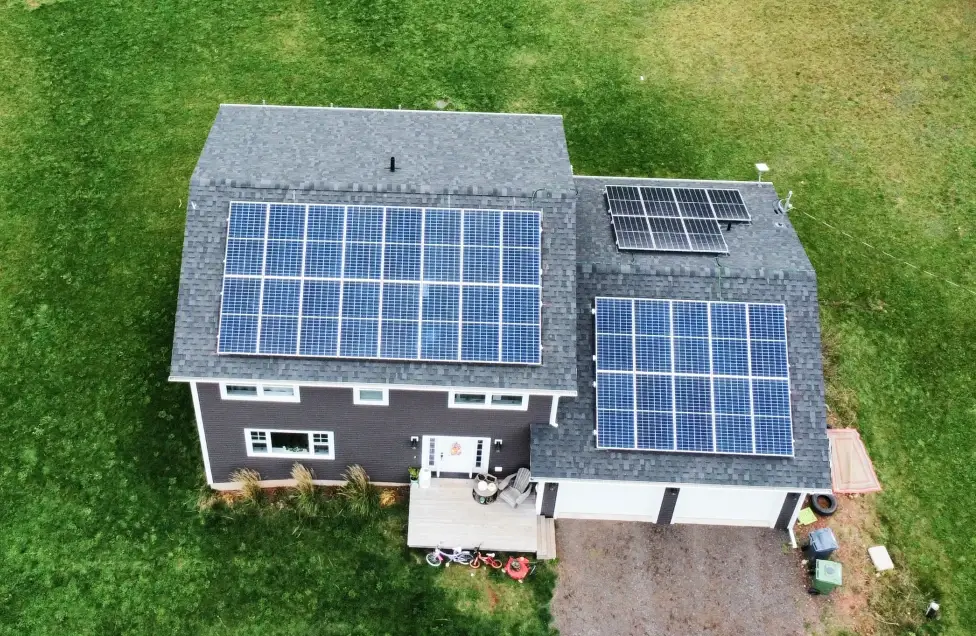 Overhead shot of a multi-array solar panel system on a two-story Prince Edward Island home, highlighting a custom design for optimal sunlight exposure and energy savings.